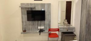a living room with a tv and a red chair at Sahasra Sree Suites Inn in Hyderabad