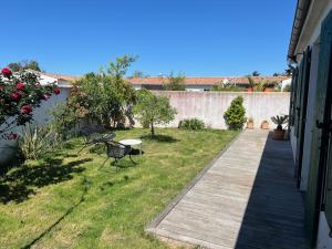ein Garten mit einem Holzsteg und einem Tisch und Stühlen in der Unterkunft La Villa des Alouettes avec piscine chauffee in Sainte-Marie-de-Ré