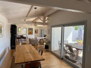 ein Esszimmer und ein Wohnzimmer mit einem Holztisch in der Unterkunft La Villa des Alouettes avec piscine chauffee in Sainte-Marie-de-Ré