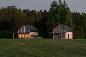 Orzechowoにあるagroturystyka Orzechowe Wzgórzeの背景に木々がある野原にある2軒の家