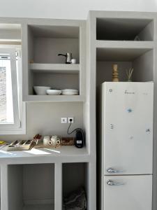 a white kitchen with a white refrigerator and shelves at Aenya Kythnos Villas in Kithnos +44 photos