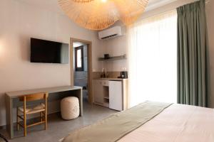a bedroom with a bed and a desk and a television at Mple Boutique Suites in Ouranoupoli