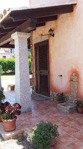 a porch of a house with a door and some plants at Villetta Bouganvillea in SantʼAnna Arresi
