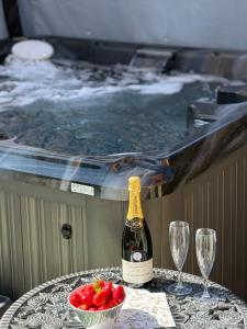 a bottle of champagne and a bowl of fruit on a table next to a tub at Luxury pair of Georgian apartments, hot tub, sea views, sleeps 12 in Bognor Regis
