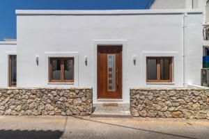a white house with a brown door and a stone wall at Antonis Traditional House in Afantou