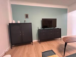 sala de estar con cómoda negra y TV de pantalla plana en Kauguri Breeze, en Jūrmala