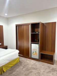 Un dormitorio con refrigerador y armarios de madera. en شقق ابراج الخير, en Abha