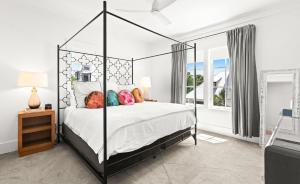 a bedroom with a large canopy bed with colorful pillows at Moonstruck in Santa Rosa Beach +51 photos