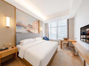 ein Hotelzimmer mit einem großen weißen Bett und einem Schreibtisch in der Unterkunft Vienna Hotel Fuzhou Mawei Banzheng Cultural Scenic Area Branch in Fuzhou