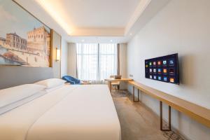 ein Hotelzimmer mit einem Bett und einem Flachbildfernseher in der Unterkunft Vienna Hotel Fuzhou Mawei Banzheng Cultural Scenic Area Branch in Fuzhou