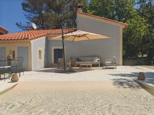 a patio with a couch and an umbrella at Lamaisonbleue in Auriol
