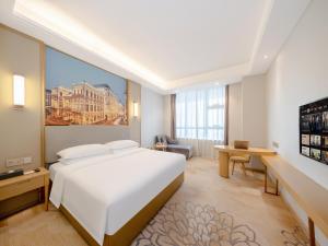 a bedroom with a large white bed and a desk at Vienna Hotel Fuzhou Mawei Banzheng Cultural Scenic Area Branch in Fuzhou