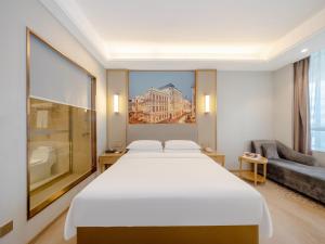 a bedroom with a large white bed and a couch at Vienna Hotel Fuzhou Mawei Banzheng Cultural Scenic Area Branch in Fuzhou