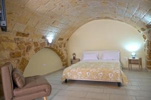 a bedroom with a bed and a chair in a stone wall at Dimora Raffaele in Mesagne