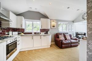 a kitchen with white cabinets and a brown leather chair at Luxury Cottage with Valley Views A Peaceful Couples Retreat in St Austell