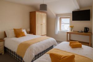 a bedroom with two beds and a tv on the wall at Ty Sunnymead Guesthouse in Aberystwyth