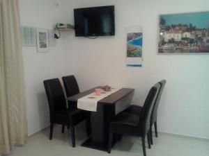 un tavolo da pranzo con sedie e una TV a parete di Apartments Barbara a Pinezići