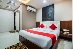 KivarliHotel O Shantivan Bus Terminal Hotel Suhagan Heights的卧室里有一张大床，配有红色枕头
