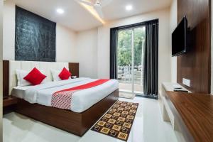 KivarliHotel O Shantivan Bus Terminal Hotel Suhagan Heights的一间卧室配有一张带红色枕头的床和电视。