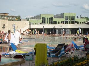 a swimming pool with chairs and people in the water at Otthon Apartman in Hajdúszoboszló