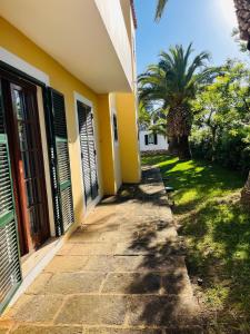 Reserva septiembre,octubre Apartamento piscina y playa junto Cap D Artrutx cerca Ciudadela في سون كسورغير: ممشى بجانب مبنى فيه نخلة