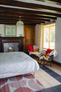 a bedroom with a bed and chairs in a room at La villa Lambert-Longière in Monnai