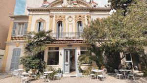 a building with tables and chairs in front of it at Hôtel Belle Meunière in Nice