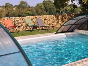 a swimming pool with two chairs and a stone wall at Ogite'85 in La Chapelle-Thémer