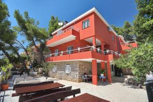 a red building with benches in front of it at Candela, No 3 in Starigrad-Paklenica