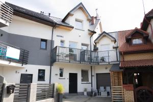 a large white house with a balcony at Pensjonat Lazytown in Pogorzelica