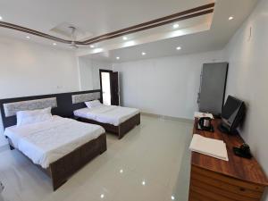 a bedroom with two beds and a tv in it at The Monarch Riverview 2BHK in Guwahati