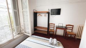 a bedroom with a bed and a table and a tv at Hôtel Belle Meunière in Nice