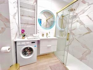 a bathroom with a washing machine and a sink at Horyzont Apartamenty-Apartament Kaszmirowy Fale Bałtyku, sauna, siłownia, plac zabaw in Kołobrzeg +8 photos