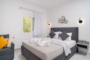 a white bedroom with a bed and a chair at Sunelia Thassos in Skala Kallirachis