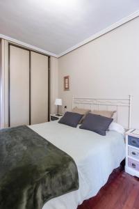 a bedroom with a large white bed with blue pillows at San Anton, Ventana al mar in Llanes