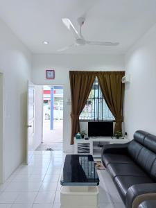 a living room with a black leather couch and a window at KAA Homestay Bajet 2 in Tawau