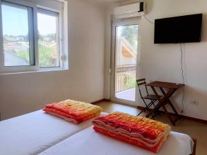 een slaapkamer met twee bedden en een flatscreen-tv bij Simple Joys Apartment in Bar