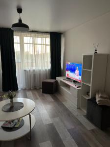 a living room with a flat screen tv and a table at Nemuno apartamentai in Panevėžys