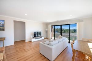a living room with a white couch and a television at MV-Giraffe 4 bedroom x 3 bathroom in Hamilton