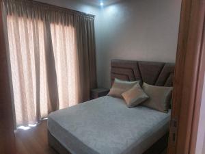 穆罕默迪耶Très joli appartement vue sur parc 5 min de la plage du centre mohammedia的卧室配有带枕头和窗户的床。
