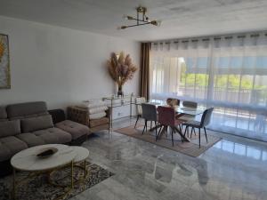 a living room with a couch and a table at Spacieux 2 pièces terrasse et piscine in Cannes