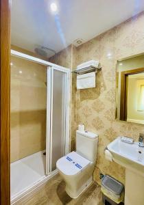 a bathroom with a toilet and a shower and a sink at Pensión Costiña in Noya