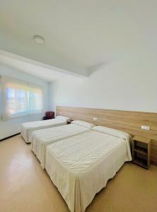 a bedroom with two beds and a window at Pensión Costiña in Noya +32 photos