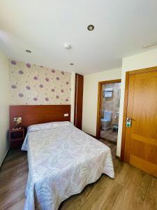 a bedroom with a large bed and a bathroom at Pensión Costiña in Noya