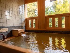 un cane seduto in una vasca da bagno con acqua di Yukairo Kikuya a Izu