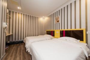 汉阳Weiyi Boutique House的配有条纹墙壁的客房内的两张床