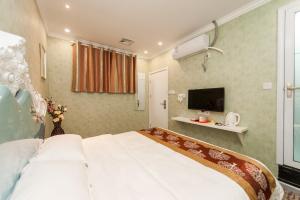 汉阳Weiyi Boutique House的卧室里有一张白色的大床和一台电视