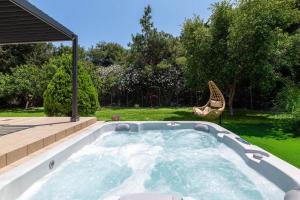 a hot tub in a backyard with a chair in a yard at Diverso Inn in Koskinou +16 photos