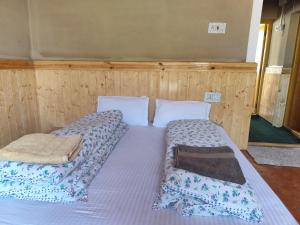 two beds in a room with wooden walls at Life inn Spiti in Kaza
