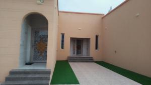 DuwaykhīlahAlwissam的一座带绿色草坪的建筑的庭院